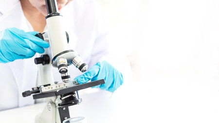 Scientists analyzing study data and evaluating microscope success for work shop. Health care researchers doing some research with dropper chemical testinglife science laboratoryの写真素材