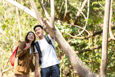 Tourist and traveler asian couple backpack enjoy and happy the jungle forest nature park . Traveler going camping and explore outdoors destination leisureの写真素材