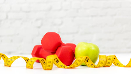 Close up green apple and dumbbell.  Healthy snack for diet planning.  Fresh  fruit with green fruit and tape measure white background.  Healthy Lifestyle Conceptの写真素材