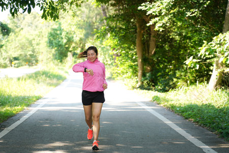 Healthy woman jogging run and workout on road outdoor. Asian runner people exercise gym with fitness session, nature park background. Health and Lifestyle Conceptの写真素材