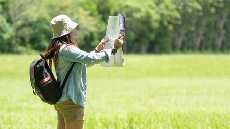 Asia women traveler and tourist hiker with backpack on big tree checks map to find directions and look binoculars in wilderness area forest.  People climb upの写真素材