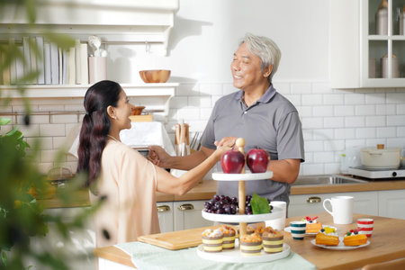 Asia happy older senior elderly couple dance waltz after cooking at kitchen room.Â  Retirement couple embraces beloved celebrating Anniversary at home.Â  Family Conceptの写真素材