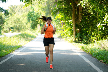 Healthy woman jogging run and workout on road outdoor. Asian runner people exercise gym with fitness session, nature park background. Health and Lifestyle Conceptの写真素材