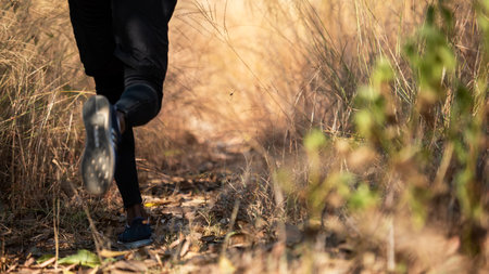 Close up legs african man runner jogging and running trail in the meadow forest . Male guy running...