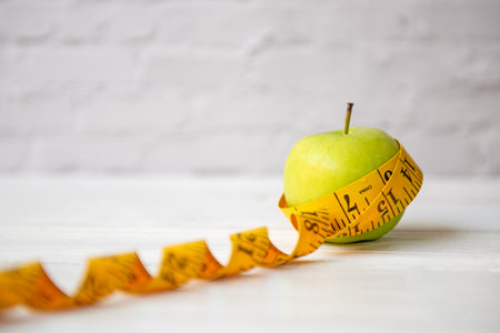 Close up fresh apple and tape measure.  Healthy snack for diet planning. White background.  Healthy Lifestyle Conceptの写真素材