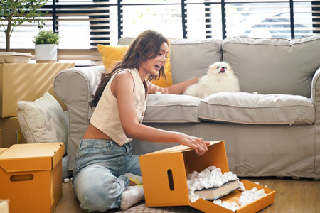 Young women with dog moving home while packing boxes together and happy in new home. Asia women investment real estate for living with family.の写真素材
