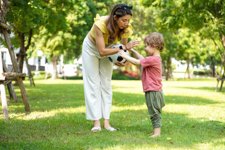 Happy family picnic and plying football in the park public on summer holiday.  Family relax and enjoying outdoor.  Family and Lifestyle Conceptの写真素材