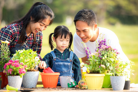 Family child girl helping parent care plant flower in garden. Young people mother, father and daughter gardening outdoor sunnyÂ  nature background. Happy and enjoyの写真素材