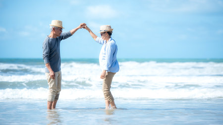 Asian Lifestyle senior couple walking and dancing chill on the beach happy in love romantic and relax time after retirement.Â  People tourism elderly family travel leisureの写真素材