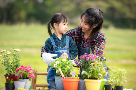 Asian  kid daughter helping mother water and sapling  the plant tree outdoors in nature spring for reduce global warming growth feature and take care nature earthの写真素材