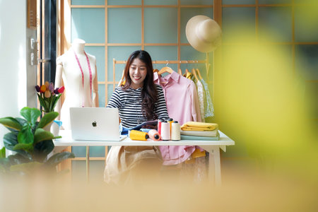 Owner business asian young women fashion designer working on her designer in the showroom,  Lifestyle Stylish tailor taking measurements on mannequin for cutting cloths in studioの写真素材