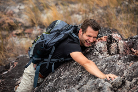 Hiker man climbing natural rocky wall with tropical valley on the background.   people backpack...