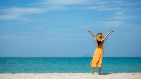 Summer vacations. Lifestyle woman relax and chill on beach background.  Asia happy young people wearing yellow dress fashion summer trips walking enjoy  tropical beachの写真素材