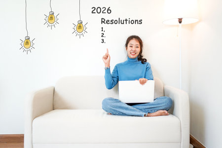 2026 resolutions with young woman pointing resolutions cheerful and happy new year with laptop on the sofa in living room.  Star together new year 2026の写真素材