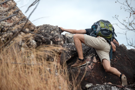Hiker man climbing natural rocky wall with tropical valley on the background.   people backpack walking trail activity camping outdoors for destination leisureの写真素材