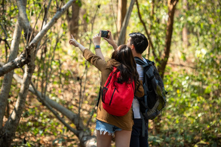 Tourist and traveler asian couple backpack enjoy and happy the jungle forest nature park . Traveler going camping and explore outdoors destination leisureの写真素材