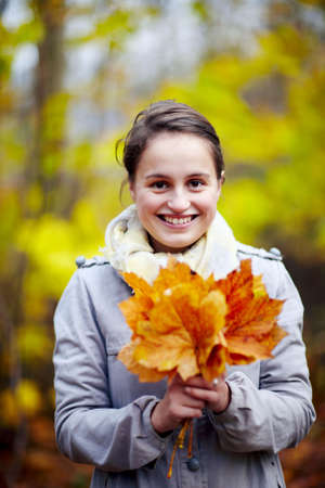 Cute young woman holding leaves in forest - autumnの写真素材