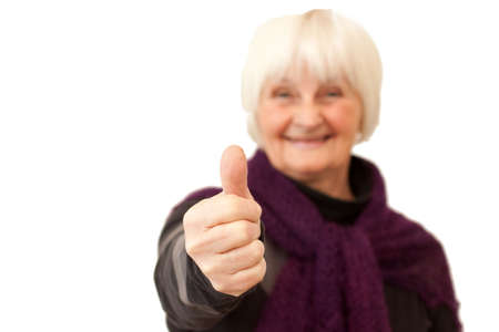 Success - smiling older woman giving you the thumbs up on whiteの写真素材