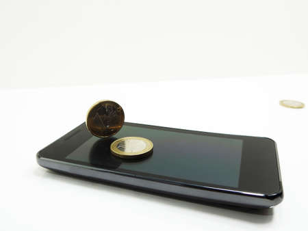 Smartphone on white background with some coinsの写真素材