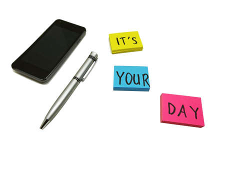 Color sticker leaves placed on white board with mobile phone and penの写真素材