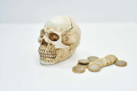Abstract composition with human skull and coins. Isolated on white background.の写真素材