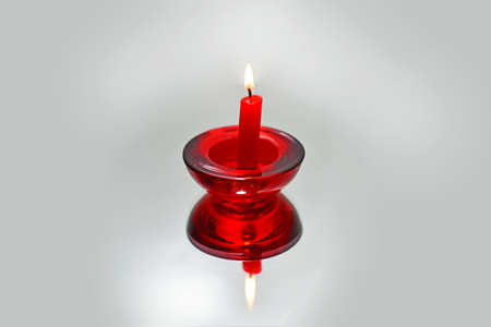 Red candle on mirror with reflection. Isolated on white background.の写真素材