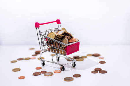 Abstract composition of buying something. Small cart with coins isolated on white background.の写真素材