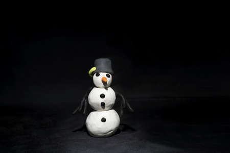 Black Friday abstract photo. Happy Merry Christmas. Snowman made from plasticine on black background.の写真素材