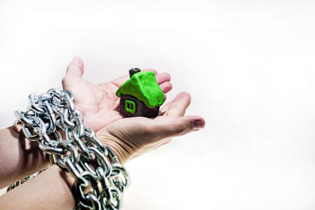 Abstract idea of property and credits. Problems with property, house, money. Small house made from Play Clay in mans hands.の写真素材