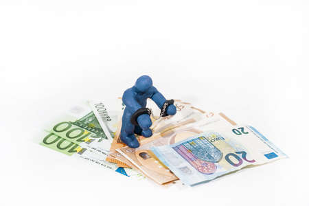 Abstract photo of financial scamming. Small figure made from Play Clay in handcuffs.の写真素材