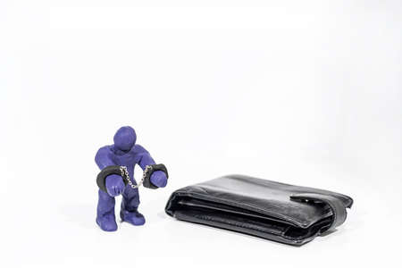 Abstract photo of theft and fraud. Small figure made from Play Clay with purse isolated on white background.の写真素材