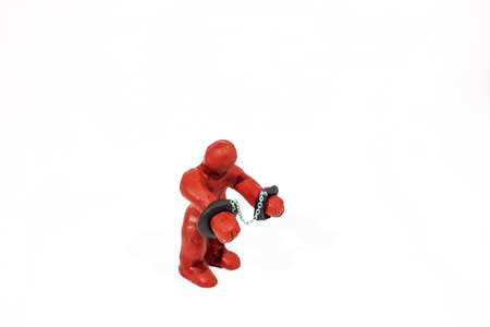 Small red figure in handcuffs. Made from Play Clay. Isolated on white background.