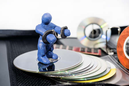 Abstract photo of the fight against content piracy. Small figure in handcuffs isolated on white background.の写真素材