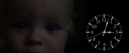 Small sad boj face in darkness. Time abstraction.の写真素材