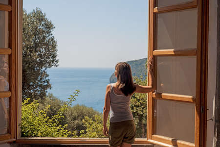 Young woman at a large open window. Summer abstract photo.