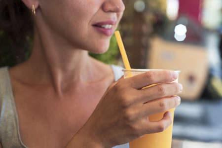 Young woman with orange juice in hand. Abstract photo of healthy food.の写真素材