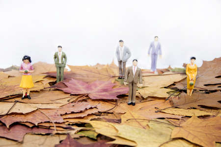 Small people figures on autumn maple leaves. Abstract photo of autumn.
