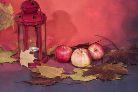 Red lantern lamp with candle and apples on red background.の写真素材