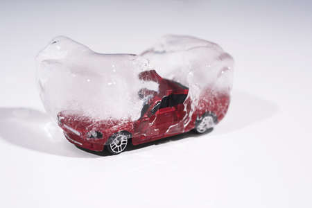 Frozen small red car in ice. Abstract winter driving conceptの写真素材