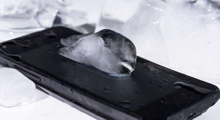 Black smartphone frozen in ice.