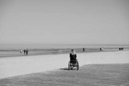 lonely disabled young woman on beach. Sunny summer day.の写真素材