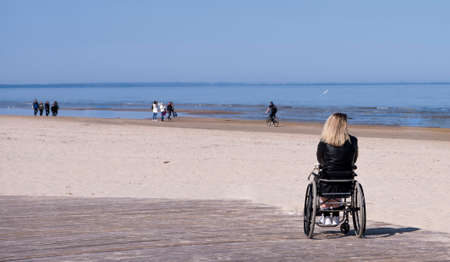 lonely disabled young woman on beach. Sunny summer day.の写真素材