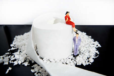 Abstract photo with toilet paper and some small people figures. Waste of time concept.
