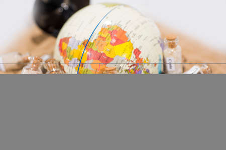 Glass test-tube with sand of different summer vacation countries. Located in sand with small globe.の写真素材