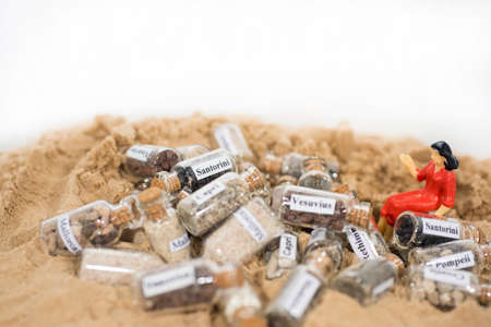 Glass test-tube with sand of different summer vacation destinations. Vacation time abstract photo.の写真素材