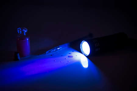 Medicine tube and syringe under ultraviolet light. Abstract photo of illness time.