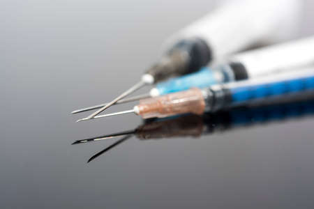 Vaccination time. Vaccine in vial with syringe on clock background. Prevention immunization illness.の写真素材