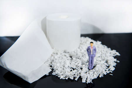 Abstract photo with toilet paper and some small people figures. Waste of time concept.