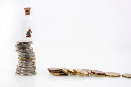 Small woman in test tube on coins. Abstract photo of financial crisis.