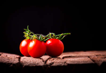 Tomatos in wooden plate on black backgroundの写真素材
